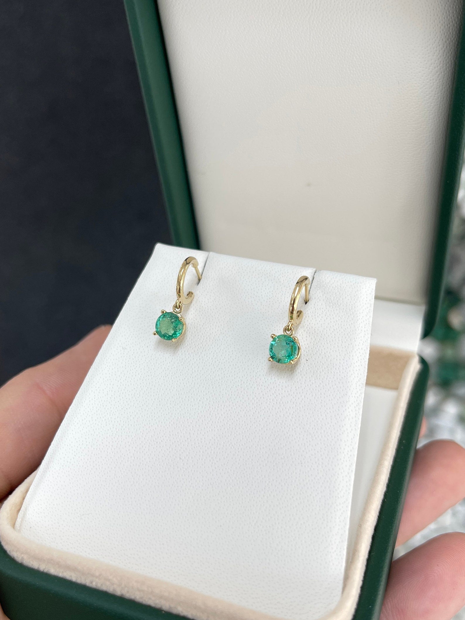 Medium dark green emerald round cut hoop earrings with four prongs in 14K gold, Colombian Emerald brand, featuring elegant earring design.