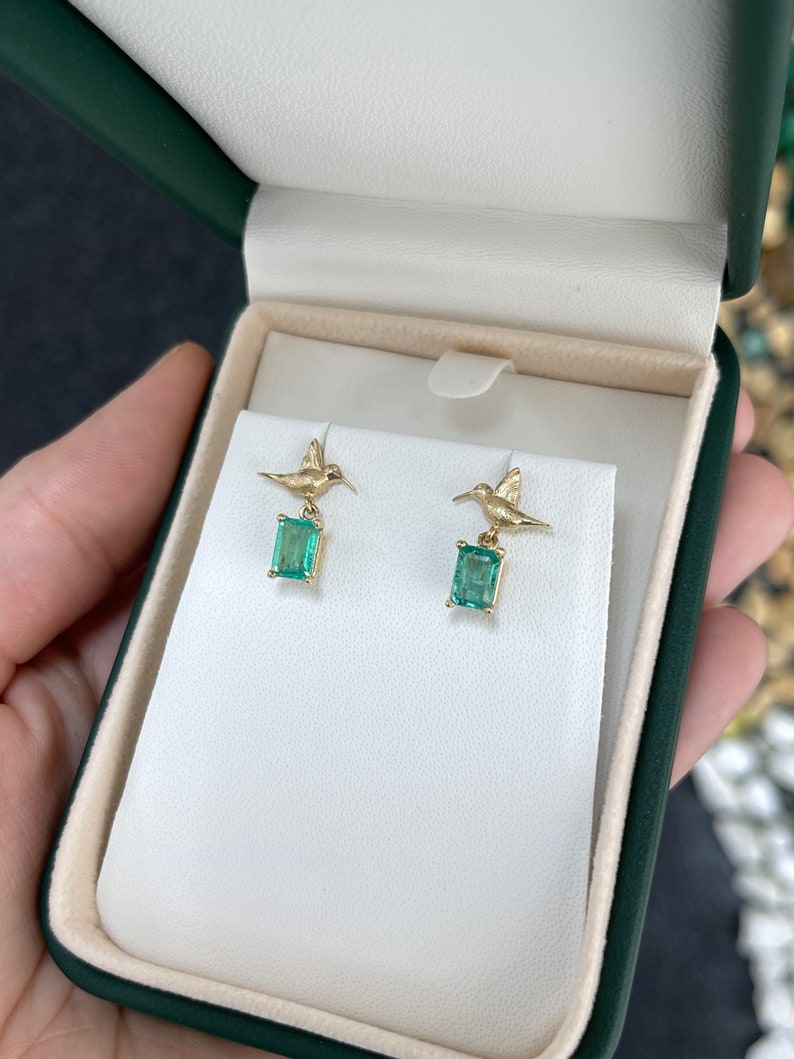 14K gold earrings with natural emeralds and hummingbird dangle design, featuring 1.90tcw Colombian emeralds.