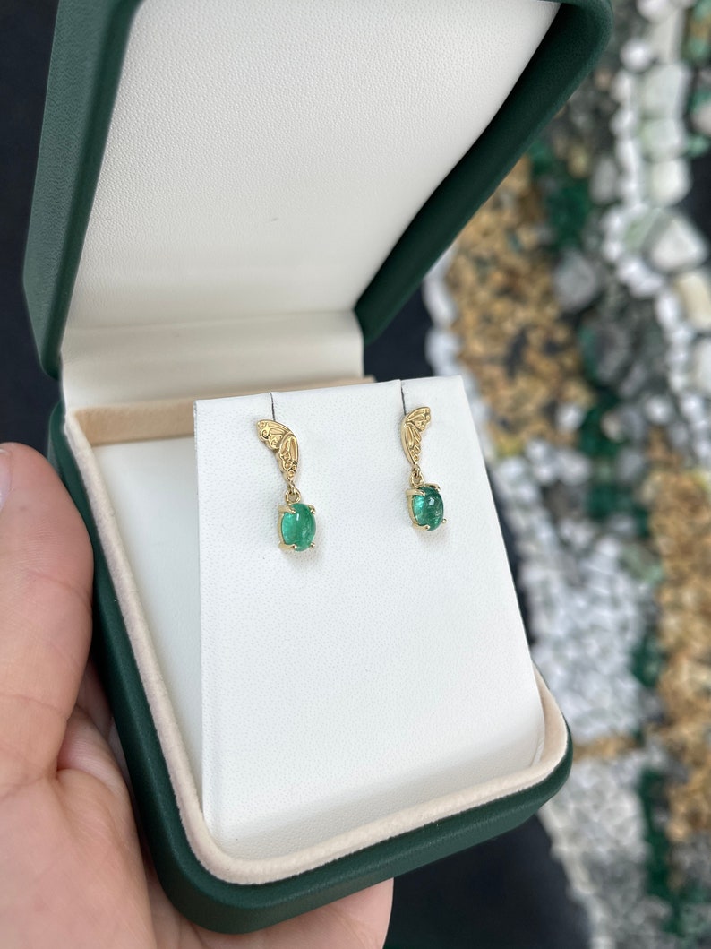 Colombian Emerald 14K yellow gold dangle earrings featuring oval-cut green cabochon emeralds with half butterfly design.