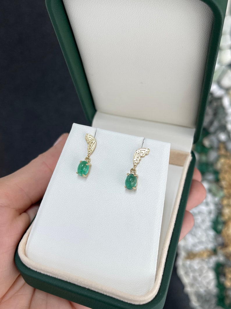 Colombian Emerald 14K yellow gold dangle earrings with oval-cut green cabochon emeralds and half butterfly design.