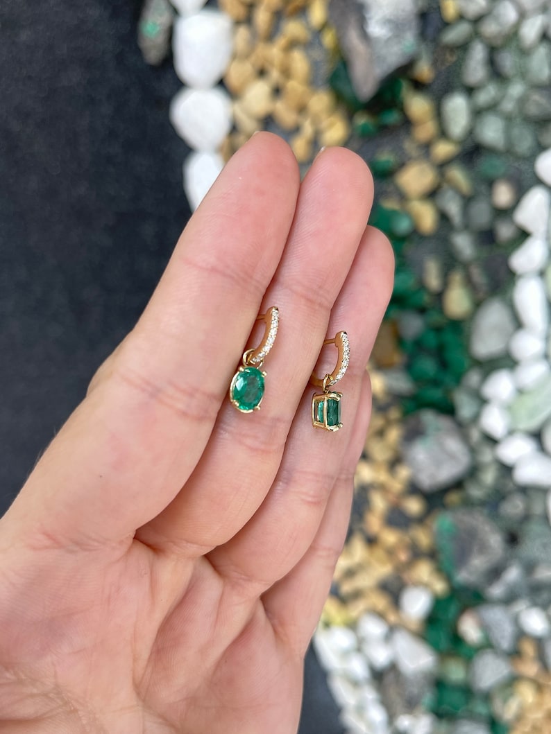 Lush green oval cut emerald dangle earrings with diamond accents in 14K gold from Colombian Emerald, showcasing elegant jewelry design.