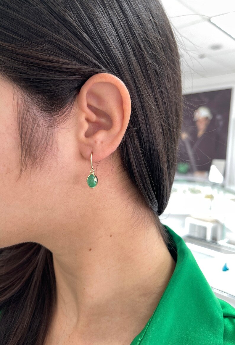 Colombian Emerald 14K gold dangle earrings featuring natural oval cabochon cut emeralds and ear wire hooks.