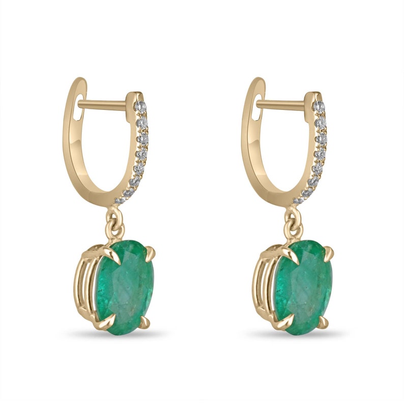 14K gold huggie dangle earrings featuring lush dark green oval cut emerald and diamond accents.