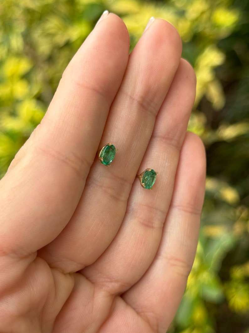 Colombian Emerald 0.80tcw 14K gold petite oval cut four prong children’s earrings featuring rich green emeralds.