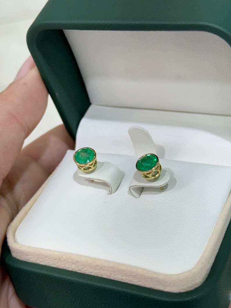 Colombian Emerald earrings with 2.14tcw round cut vivid green emeralds in bezel settings, featuring window details, on a white background.