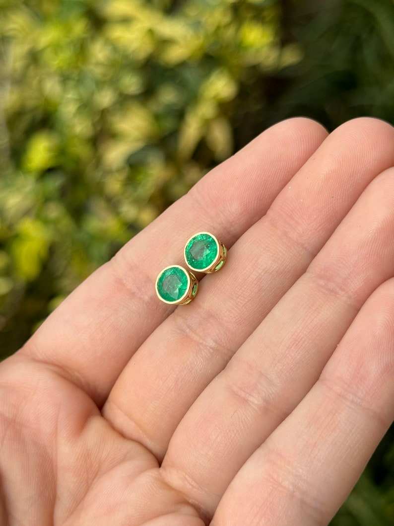Colombian Emerald earrings with 2.14ctw round-cut vivid green emeralds in 18K bezel setting, featuring window details.