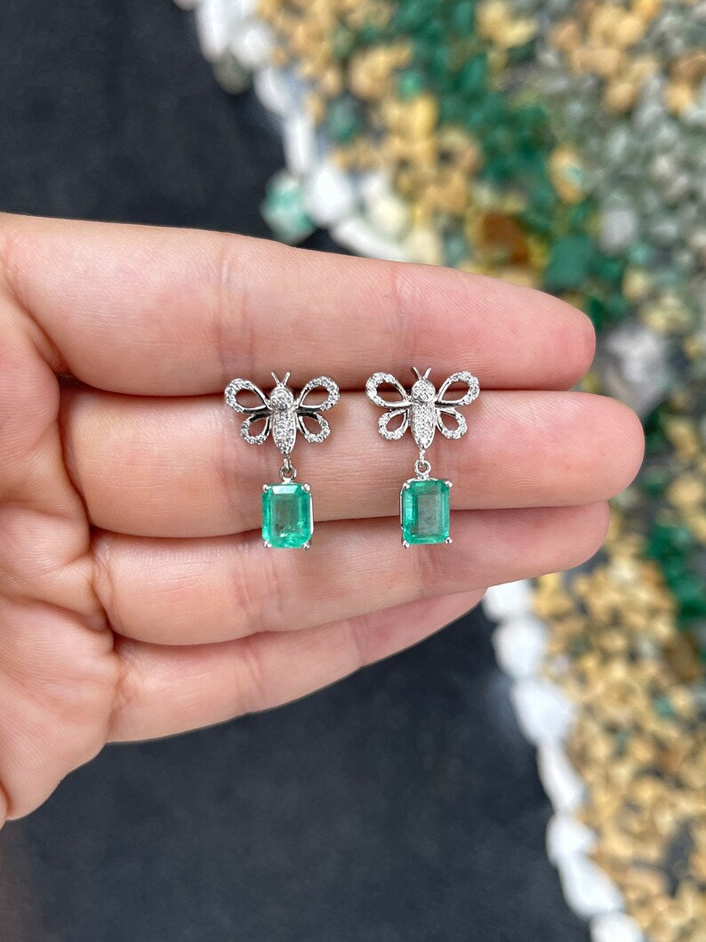 14K gold emerald butterfly dangle earrings with pave diamonds, featuring medium green Colombian emeralds and intricate design.