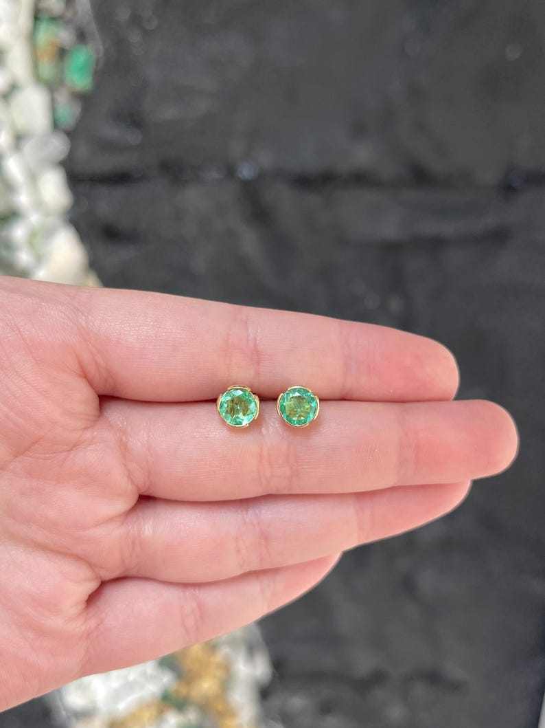 14K Colombian Emerald round stud earrings with 2.0 carats total weight, featuring semi-bezel settings and vibrant green gemstones.