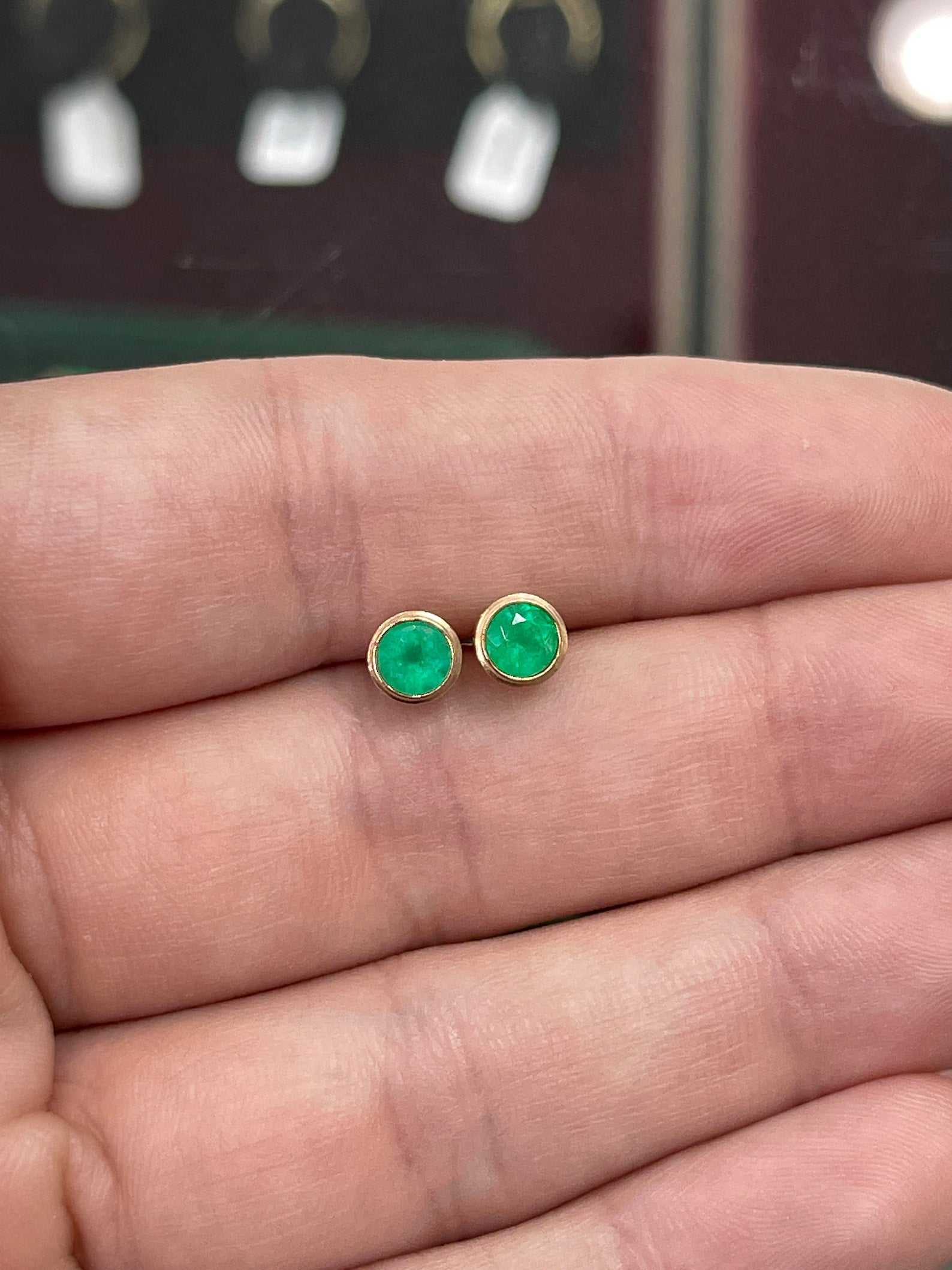 14K gold Colombian emerald stud earrings with 1.40 carats round-cut bezel-set rich green emeralds.