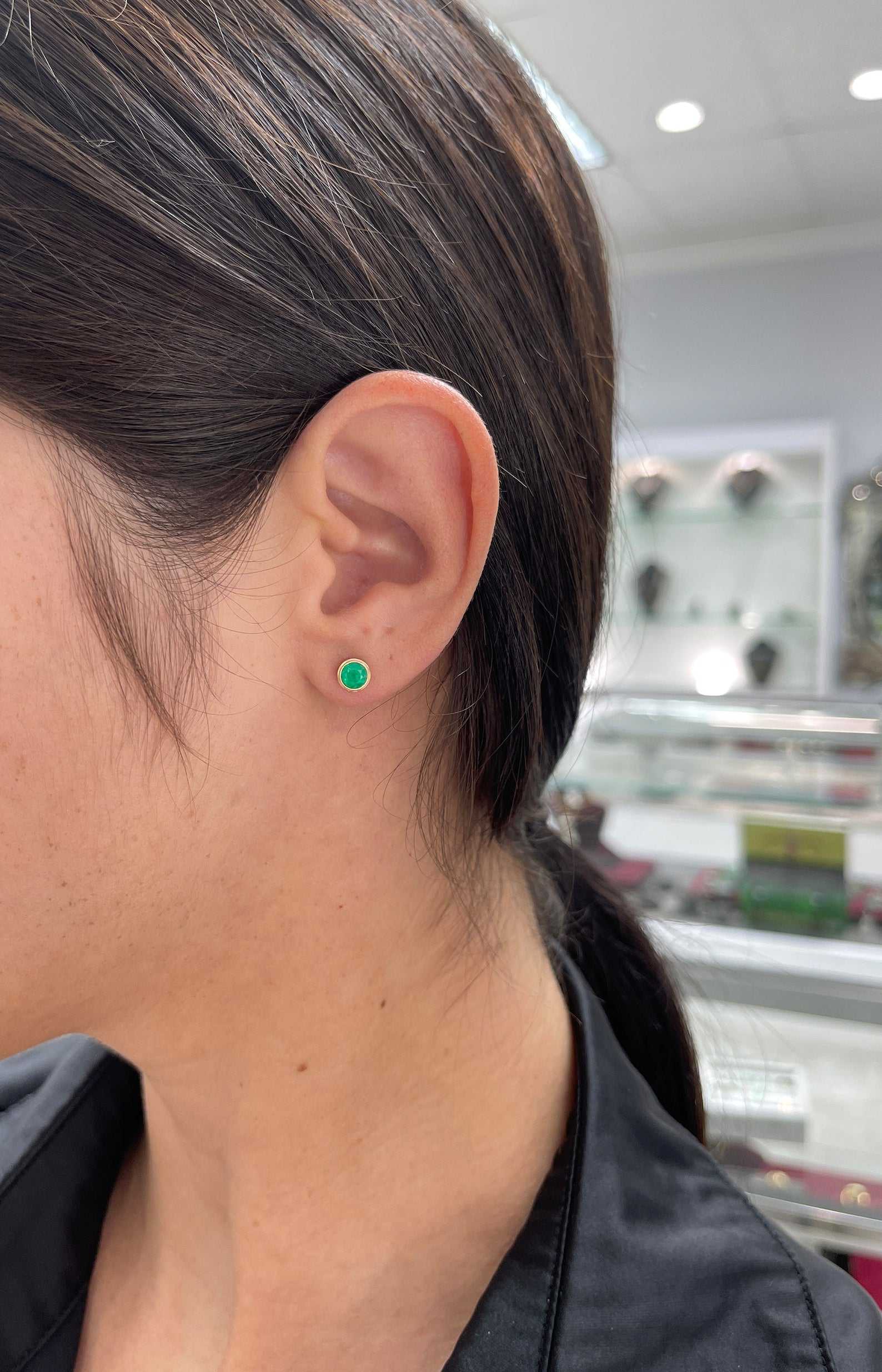 Colombian Emerald 1.40tcw round cut bezel set stud earrings in 14K yellow gold featuring rich green emeralds.