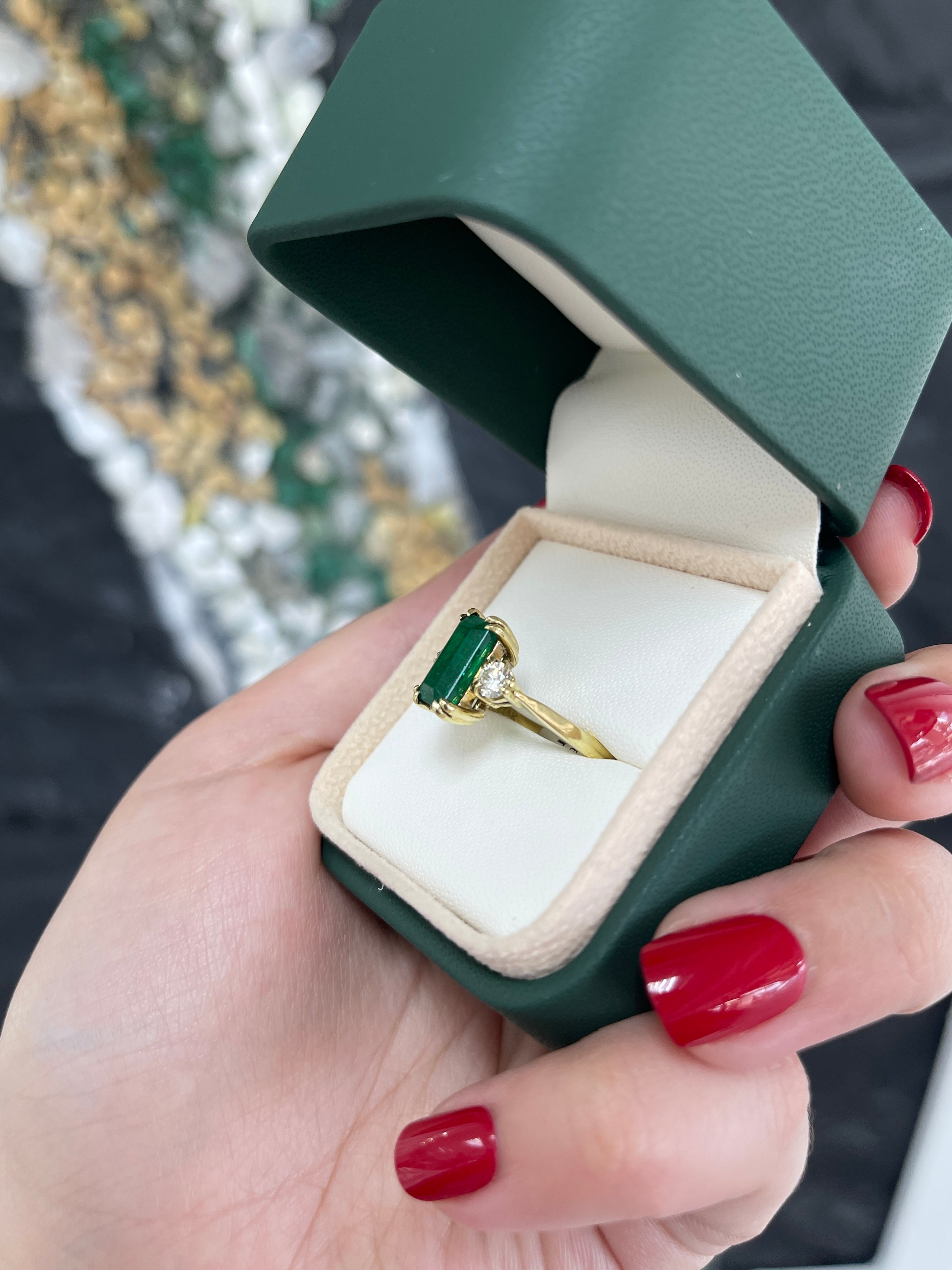 Colombian Emerald 18K gold engagement ring with 2.78tcw emerald cut and round diamonds in a three-stone design.