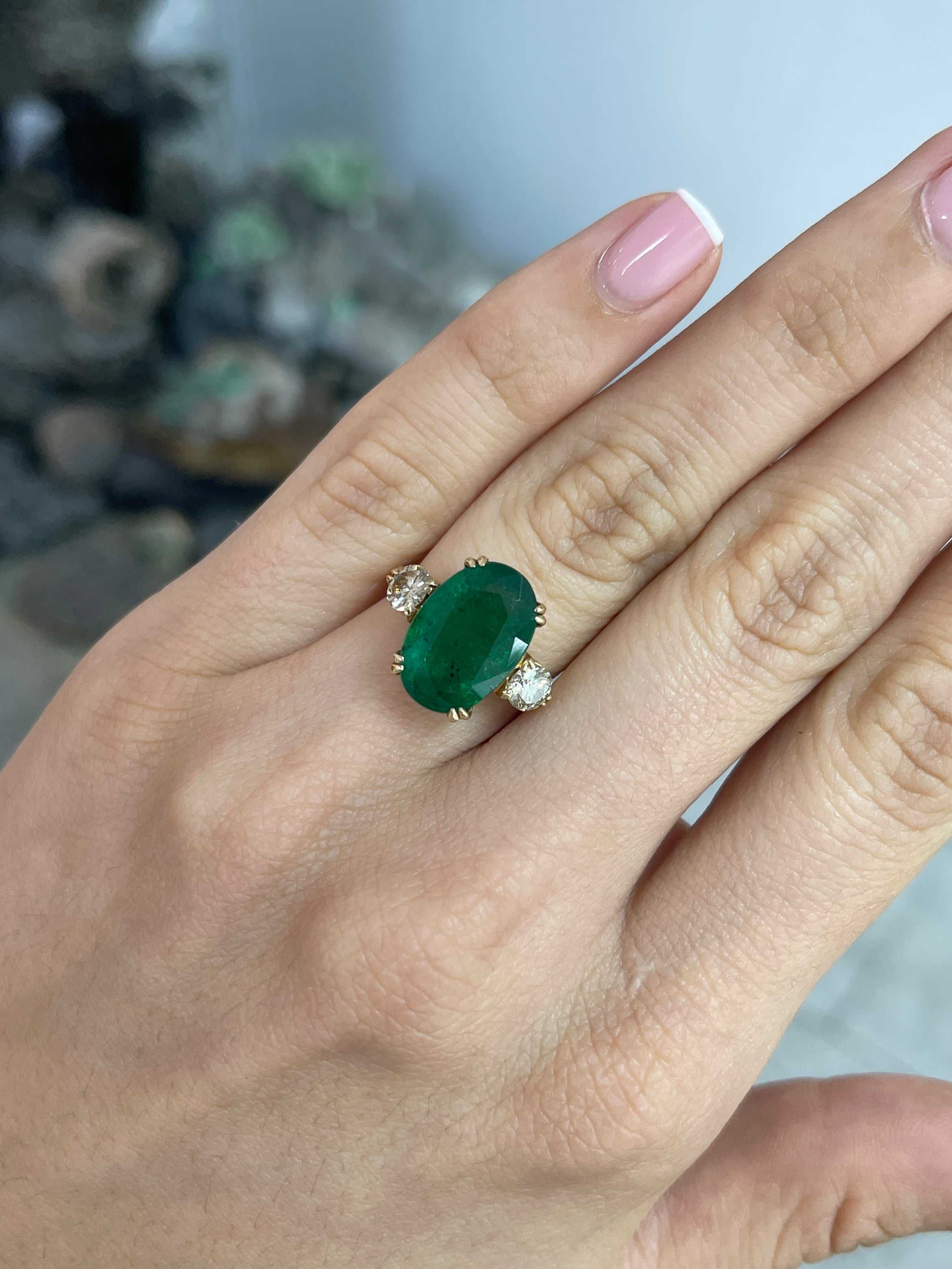 Dark green oval emerald and round diamonds in a 14K Colombian Emerald engagement ring with double prong setting.