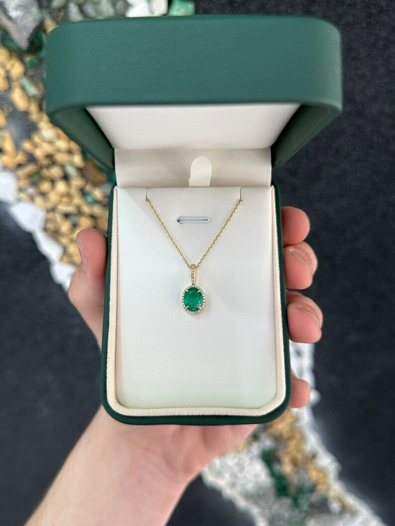 Deep green oval emerald pendant with diamond halo on a gold chain, featuring Colombian Emerald branding.