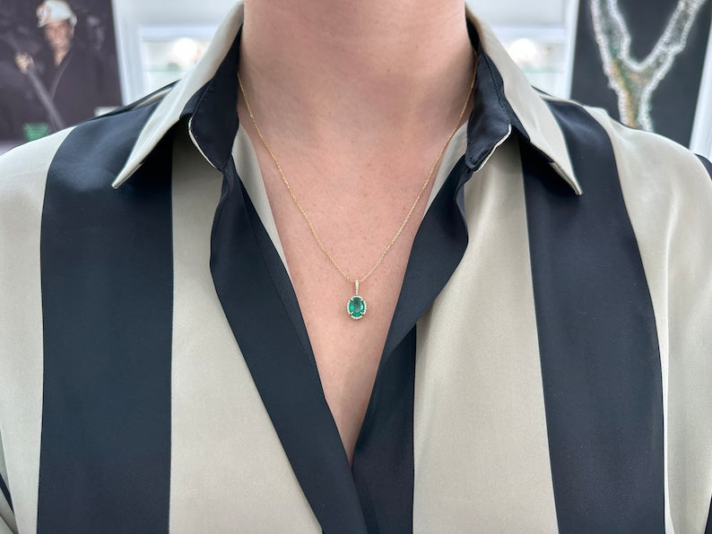 Deep green oval emerald pendant necklace with diamond halo, 14K gold setting, Colombian Emerald brand, showcasing elegant jewelry design