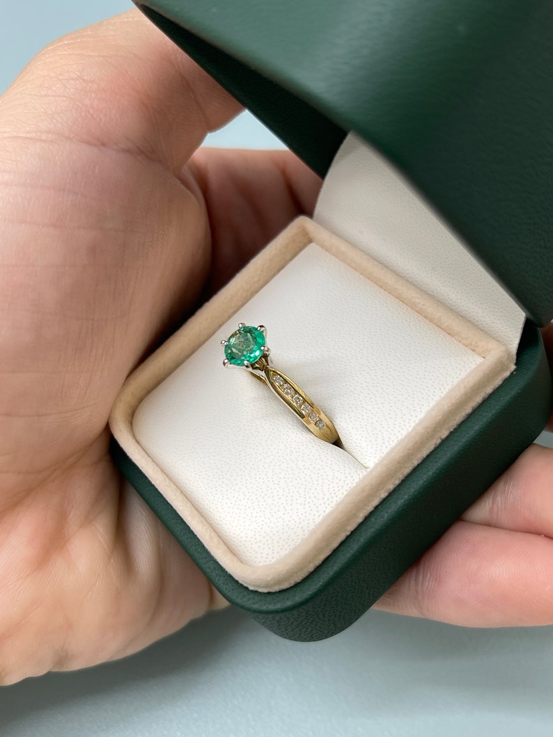 Two-toned 14K emerald and diamond accent engagement ring with round cut stones and six prongs by Colombian Emerald.