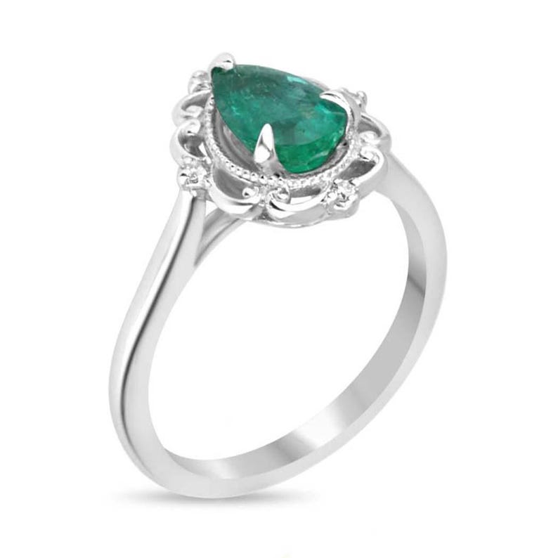 Platinum engagement ring with pear-cut emerald and diamond accents, ornate filigree crown and scroll design by Colombian Emerald