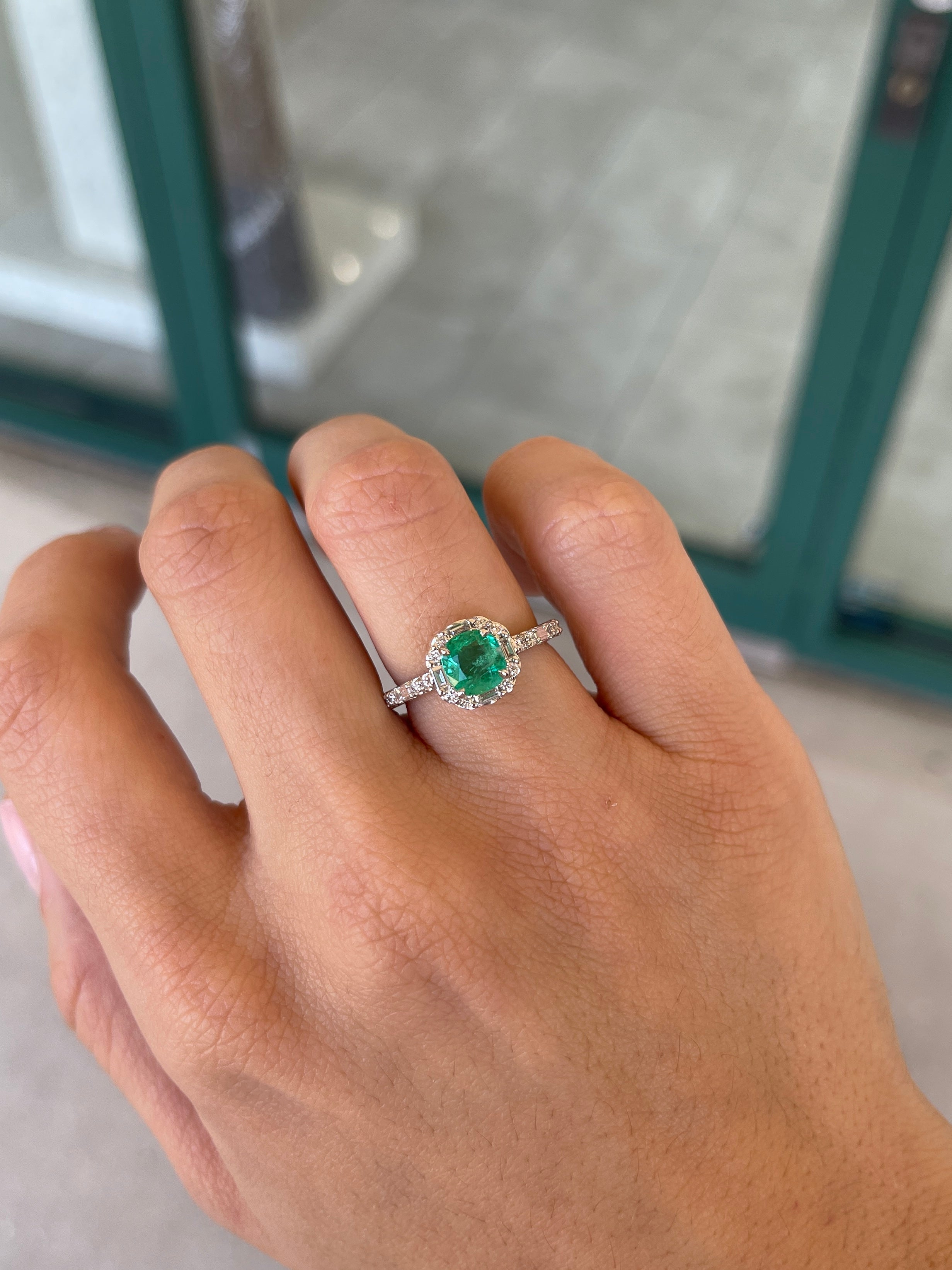 14K Colombian Emerald and diamond halo engagement ring featuring a 1.55tcw cushion cut vivid green emerald and round baguette diamonds