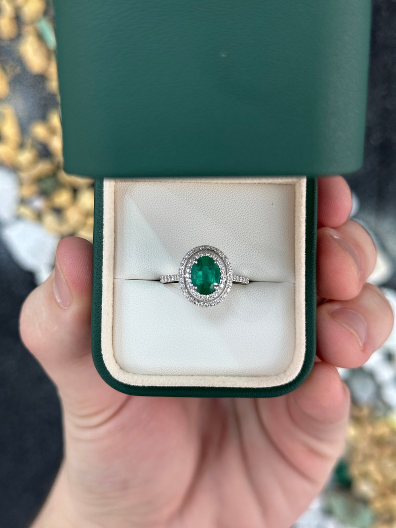 Colombian Emerald engagement ring with 8x6 oval cut rich green emerald and double diamond halo in 14K white gold.
