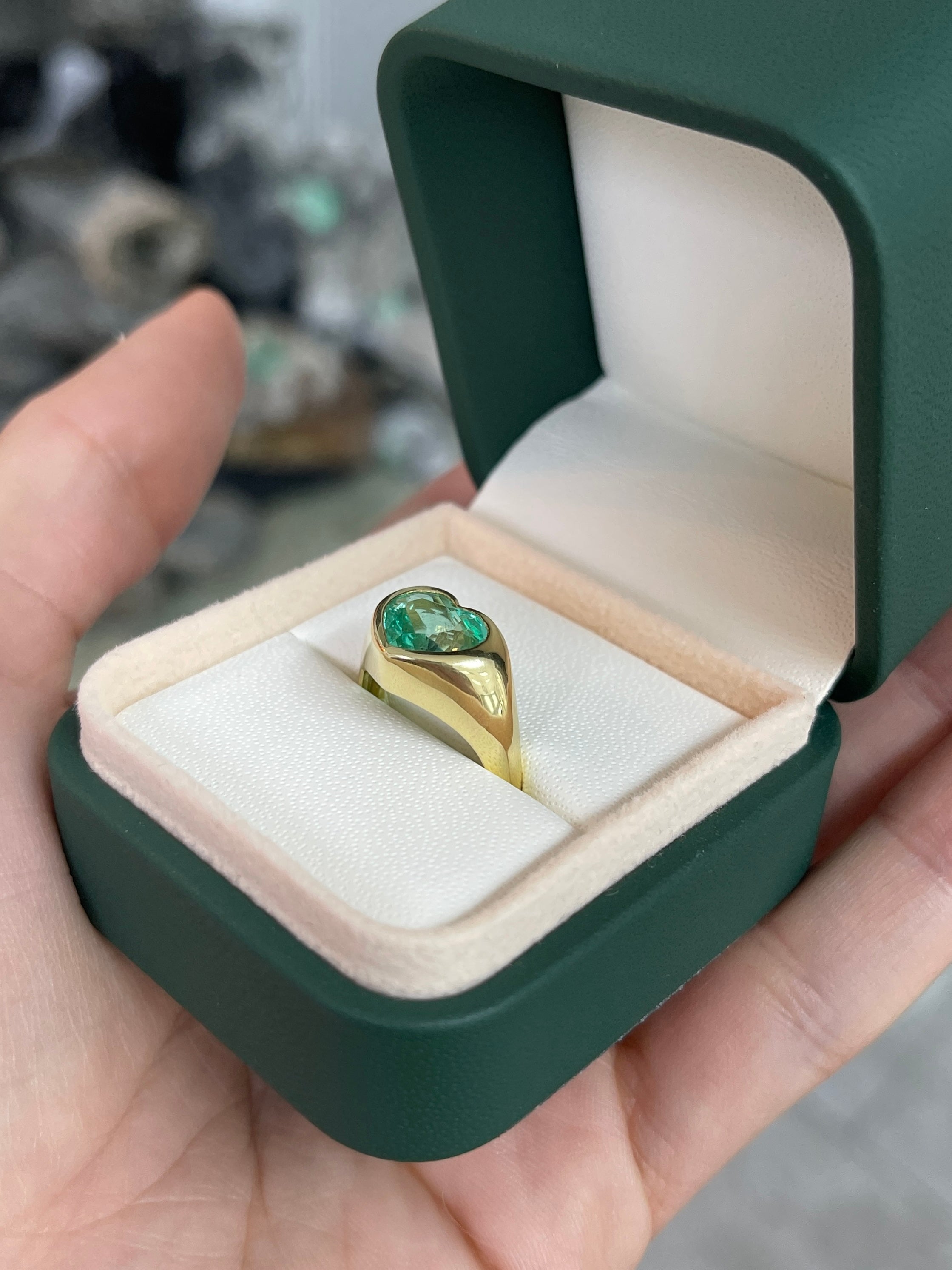 Unisex 18K gold heart-cut Colombian emerald bezel solitaire engagement ring with remaining balance, shown in close-up image.