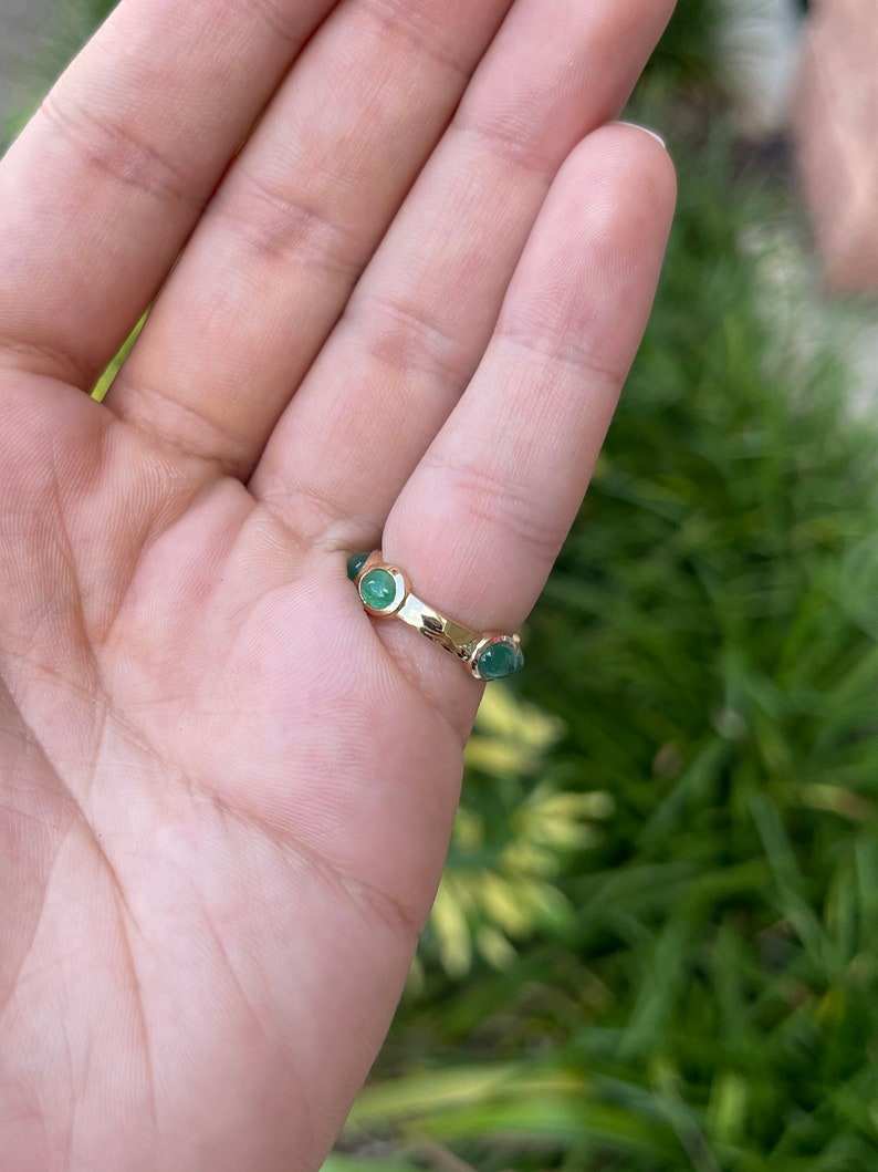 Ladies emerald eternity ring featuring a 3.60tcw east-to-west oval cabochon-cut Colombian emerald in 14K yellow gold, size 5.25.
