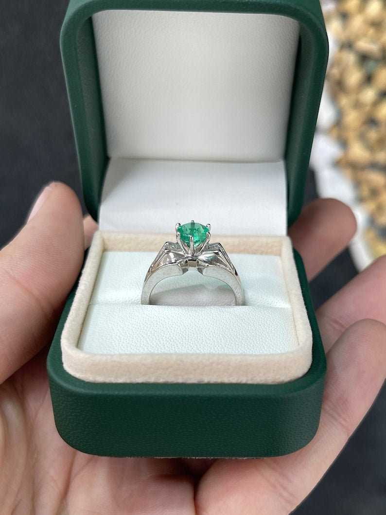 Colombian Emerald ladies ring featuring 1.25ctw round emerald, tapered baguette diamonds, 18K white gold, six-prong setting.