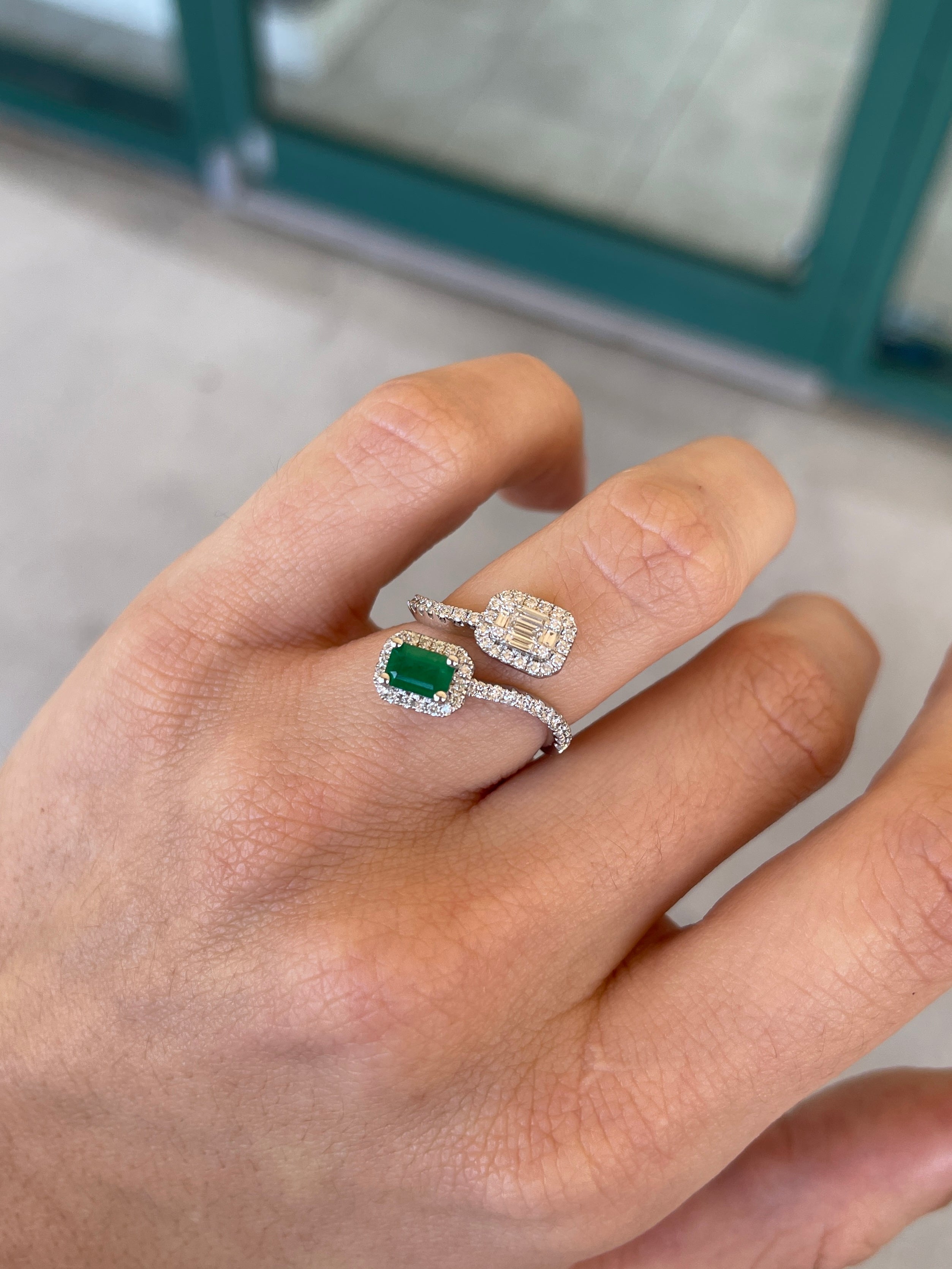 Ladies emerald ring featuring a 1.51 tcw Colombian emerald in a 14K white gold bypass shank with round and baguette cut green emeralds.