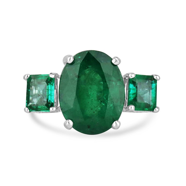 Ladies 14K gold emerald trilogy ring featuring three dark green oval cut natural Colombian emeralds with diamond accents.