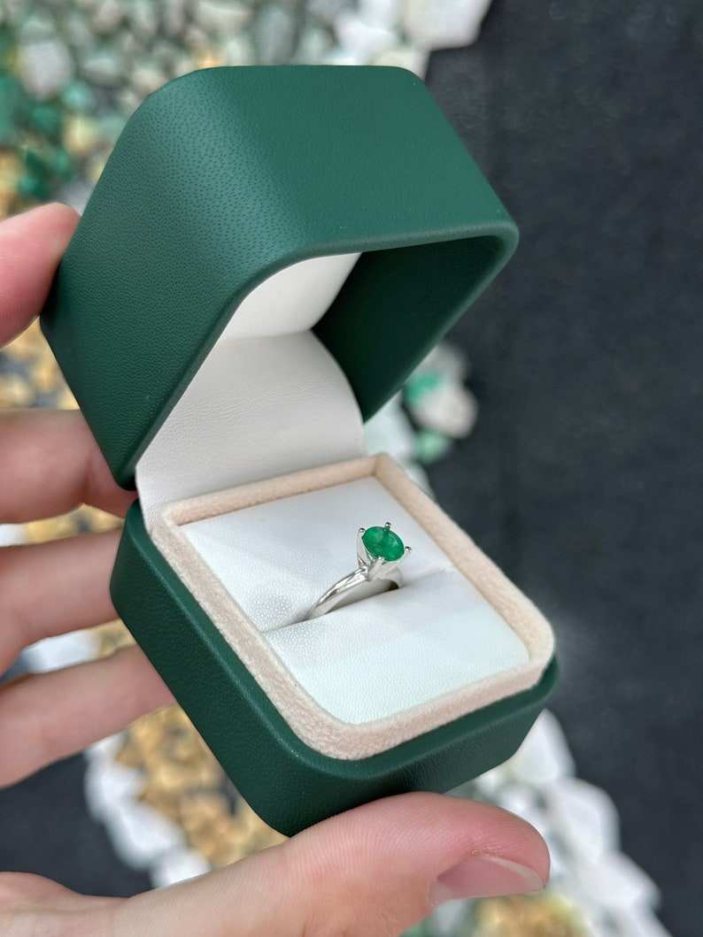 14K white gold engagement ring with a 0.93ct medium dark green round-cut emerald in a 4-prong solitaire setting