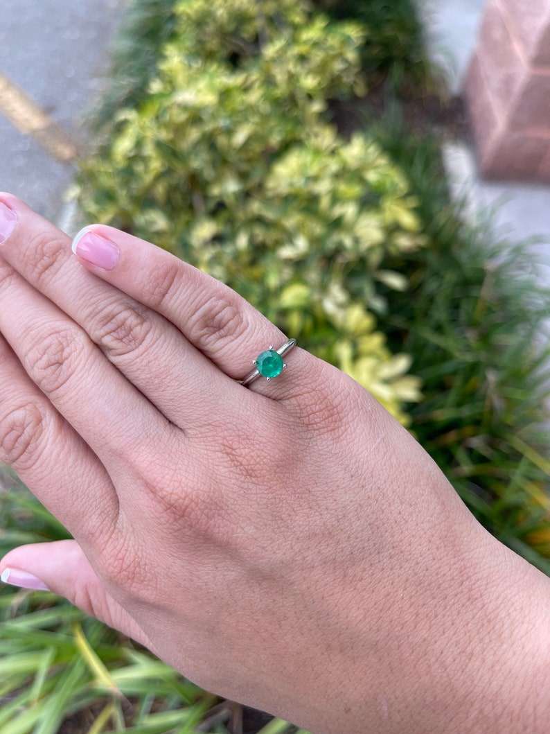 14K white gold engagement ring with a 0.93ct medium dark green round cut emerald in a 4-prong solitaire setting.