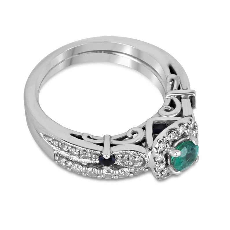 Intricate 14K gold engagement ring with natural emerald and sapphire accents, featuring 1.44tcw diamonds and Colombian Emerald branding.