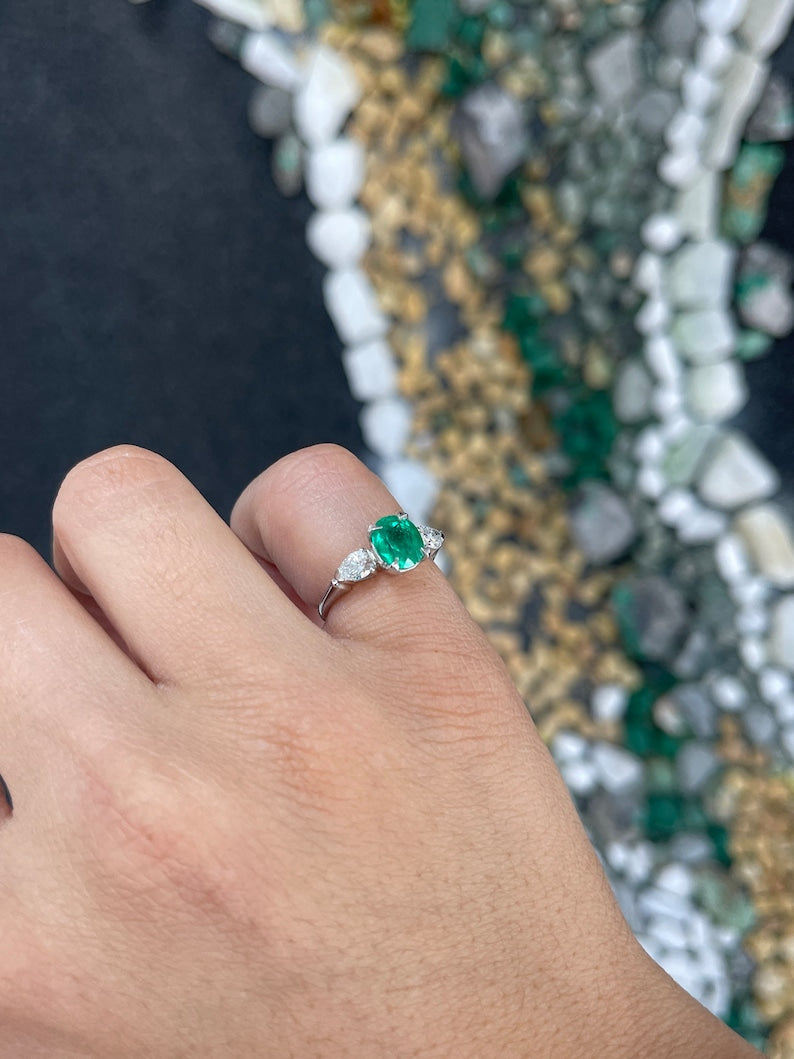 Colombian Emerald three-stone engagement ring featuring a vivid dark green emerald with diamond accents on a silver band.