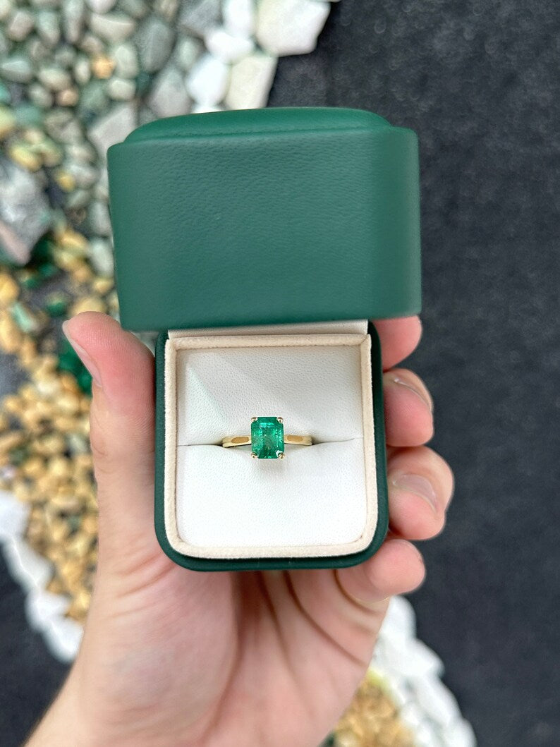 14K gold emerald cut green emerald solitaire ring with 4 prongs on a right hand, featuring a vivid medium dark green gemstone.