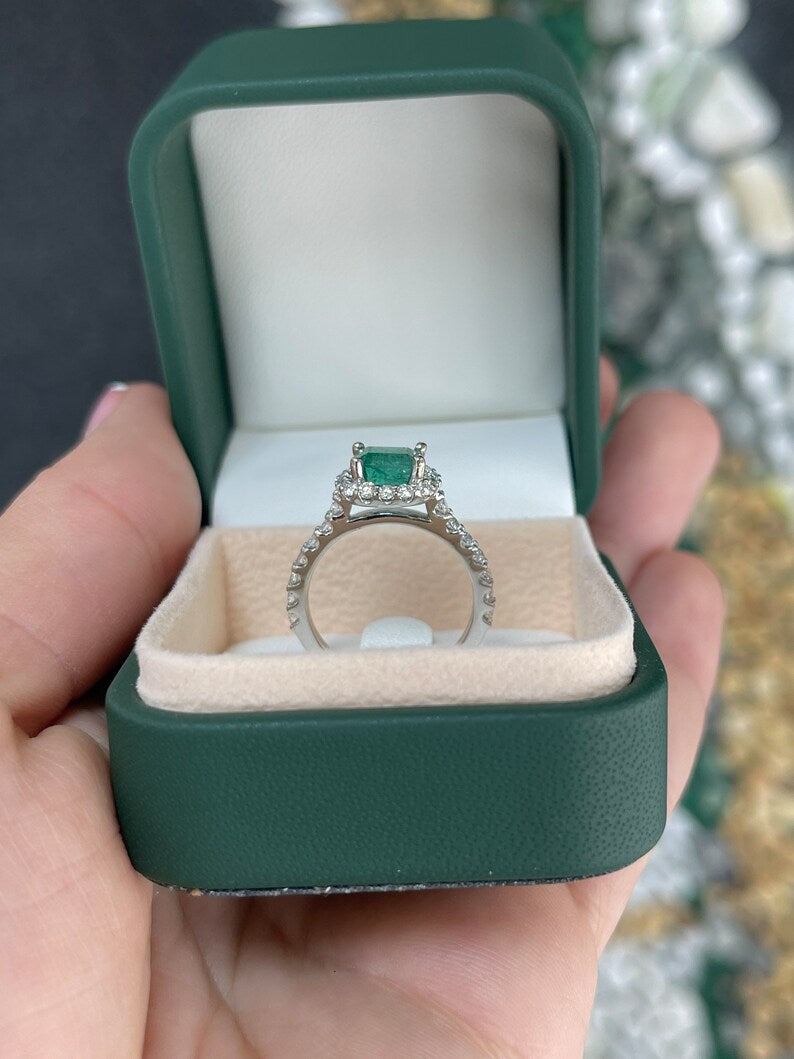 East to West Emerald and diamond halo engagement ring in 14K gold by Colombian Emerald, showcasing a central green emerald with surrounding diamonds.