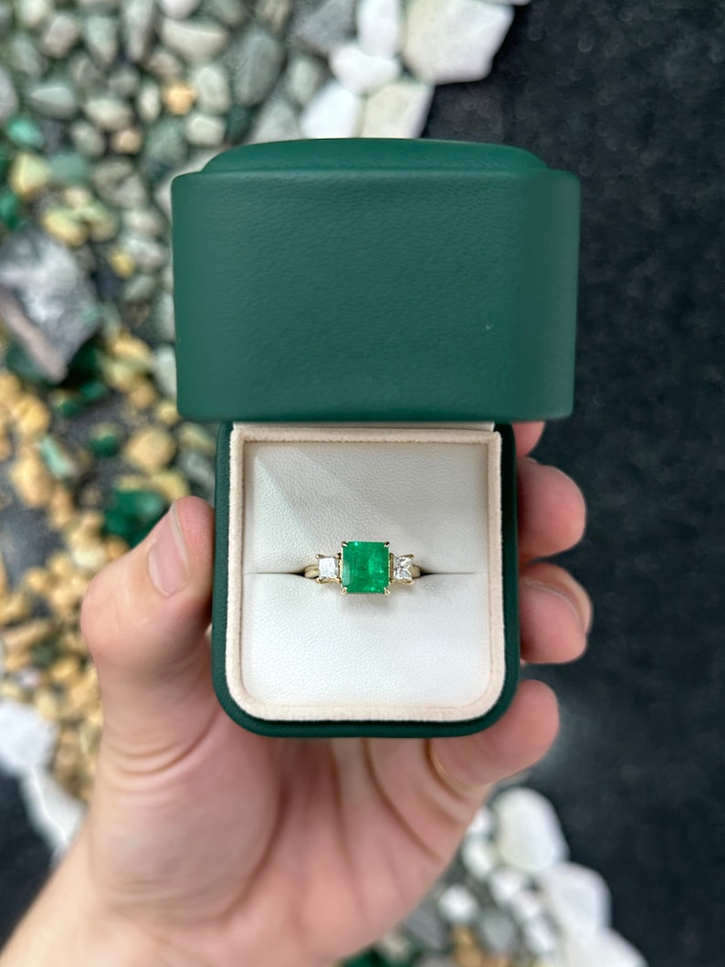 Colombian Emerald and princess cut diamond 3-stone ring in 14K gold, featuring vibrant green emeralds and sparkling diamonds.