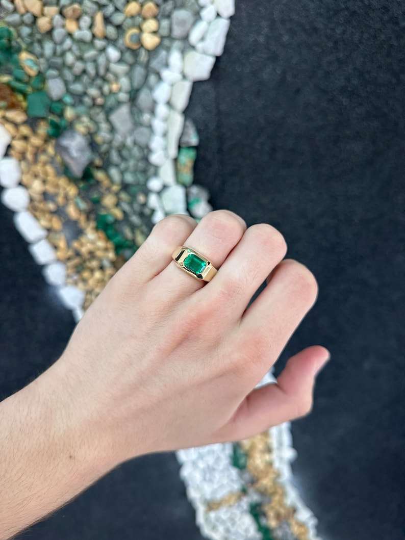 Colombian Emerald 2.70ct AAA+ vivid green east-west emerald cut solitaire gypsy ring with a sleek band and intricate detailing.