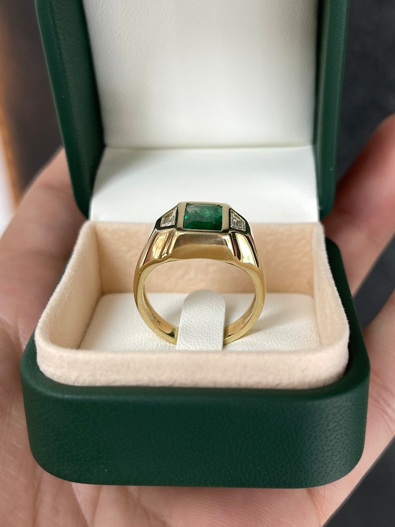 Unisex 18K gold ring featuring a 3.30tcw dark green emerald and three diamond accents, crafted by Colombian Emerald.