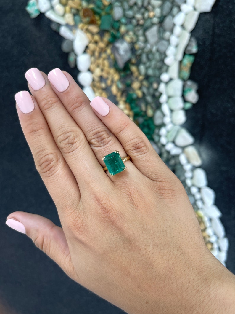 Colombian Emerald 7.90ct large emerald-cut solitaire ring with double claw prongs on a right hand ring setting.