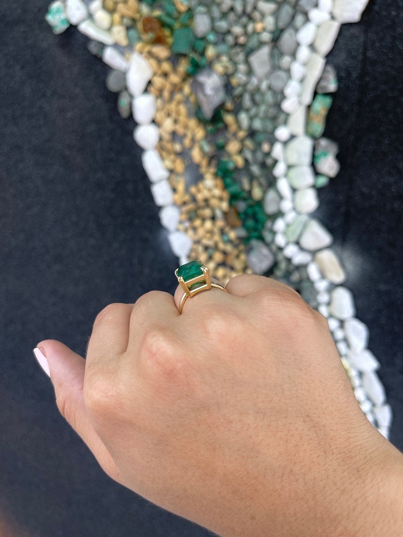 Large 7.90ct emerald cut Colombian Emerald solitaire ring with double claw prongs, designed for right hand wear.