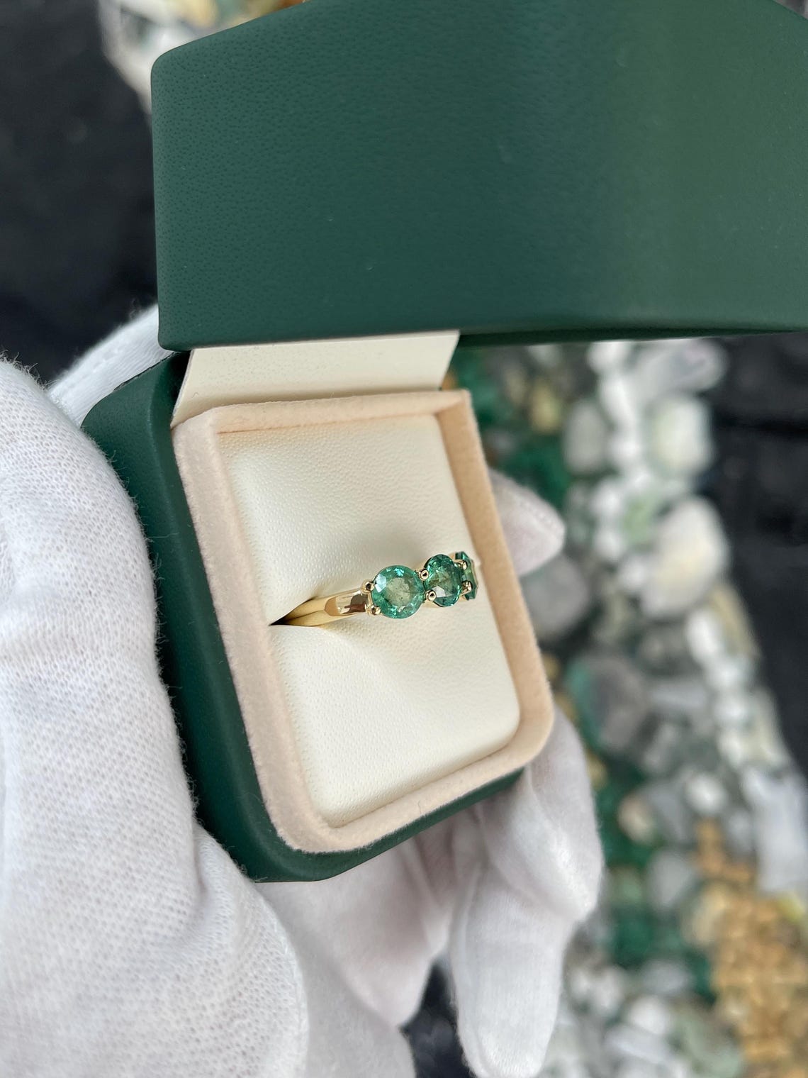 Two 2.20 carat round emerald three-stone band ring in 14K gold with prong setting, featuring rich green Colombian emeralds.