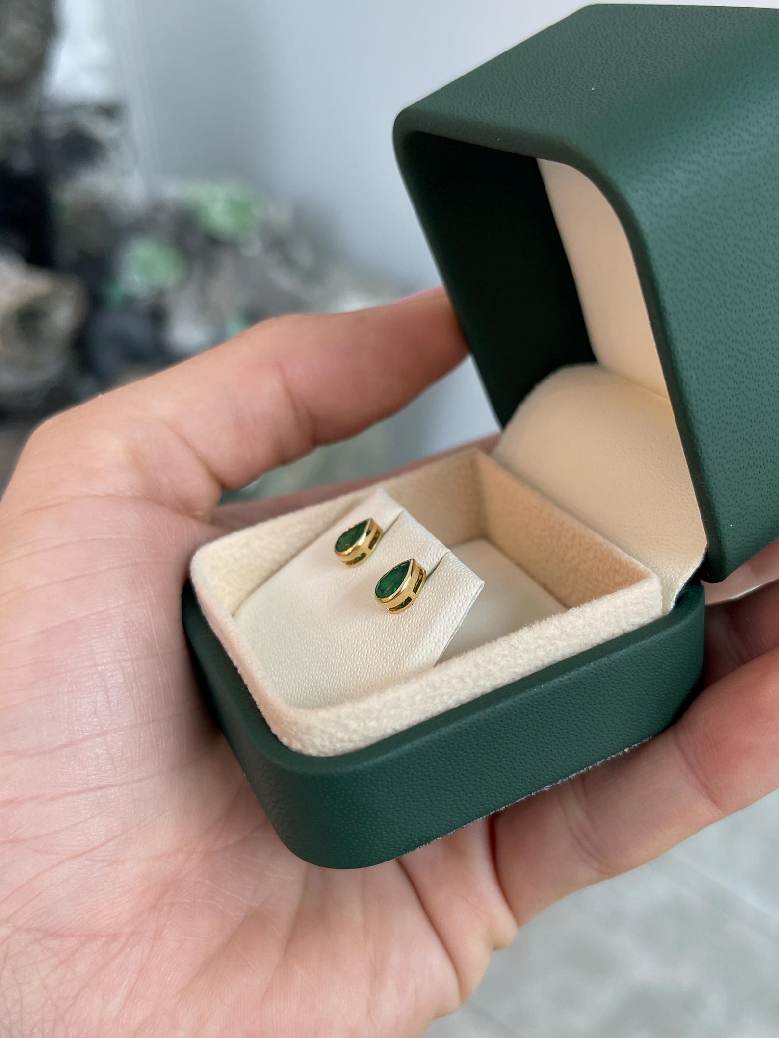 Rich green pear cut Zambian emerald stud earrings with bezel setting from JR Colombian Emeralds, showcasing vibrant gemstone detail.