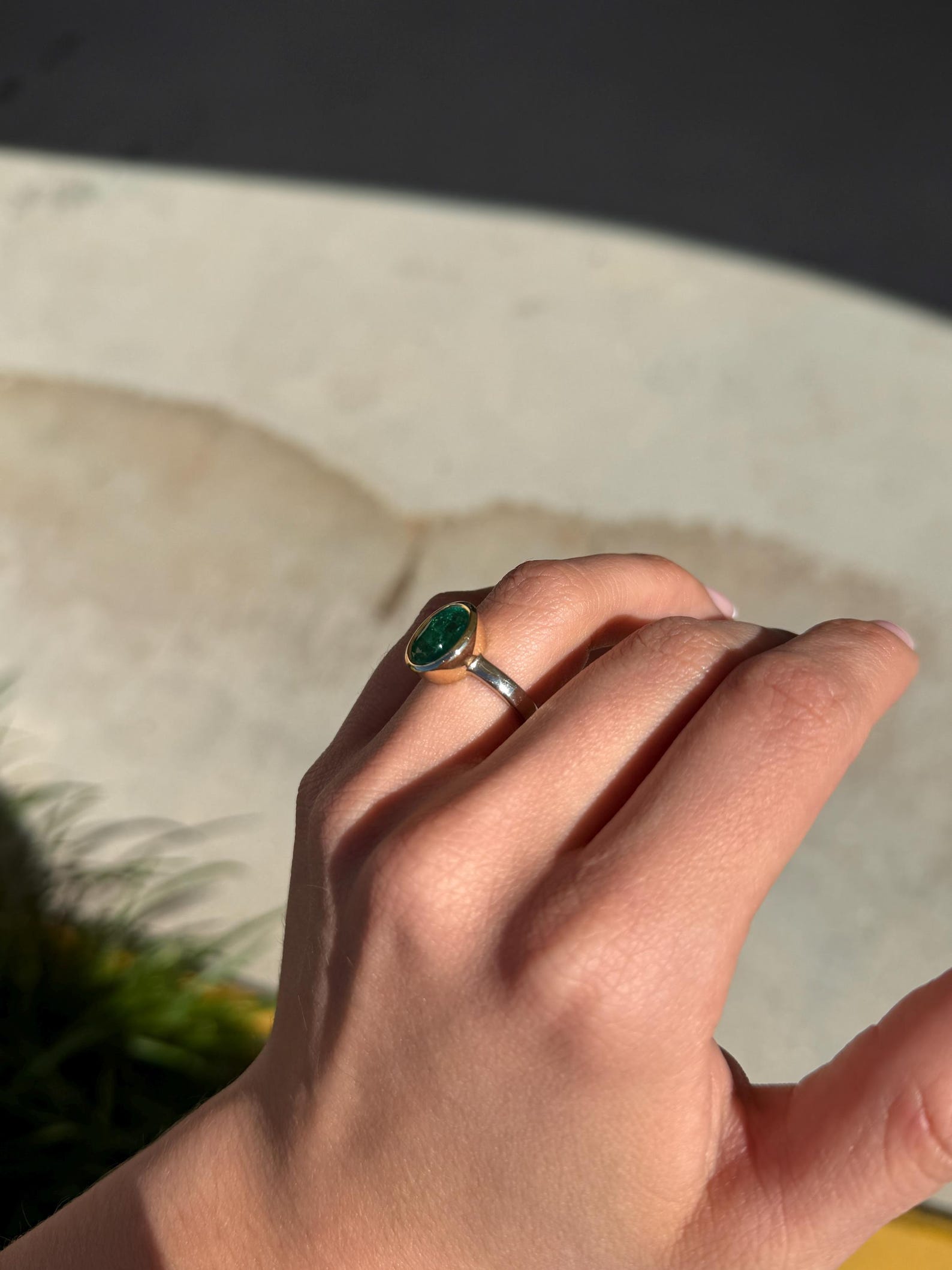 vivid green emerald ring in two‑toned 14k gold bezel set with oval emerald