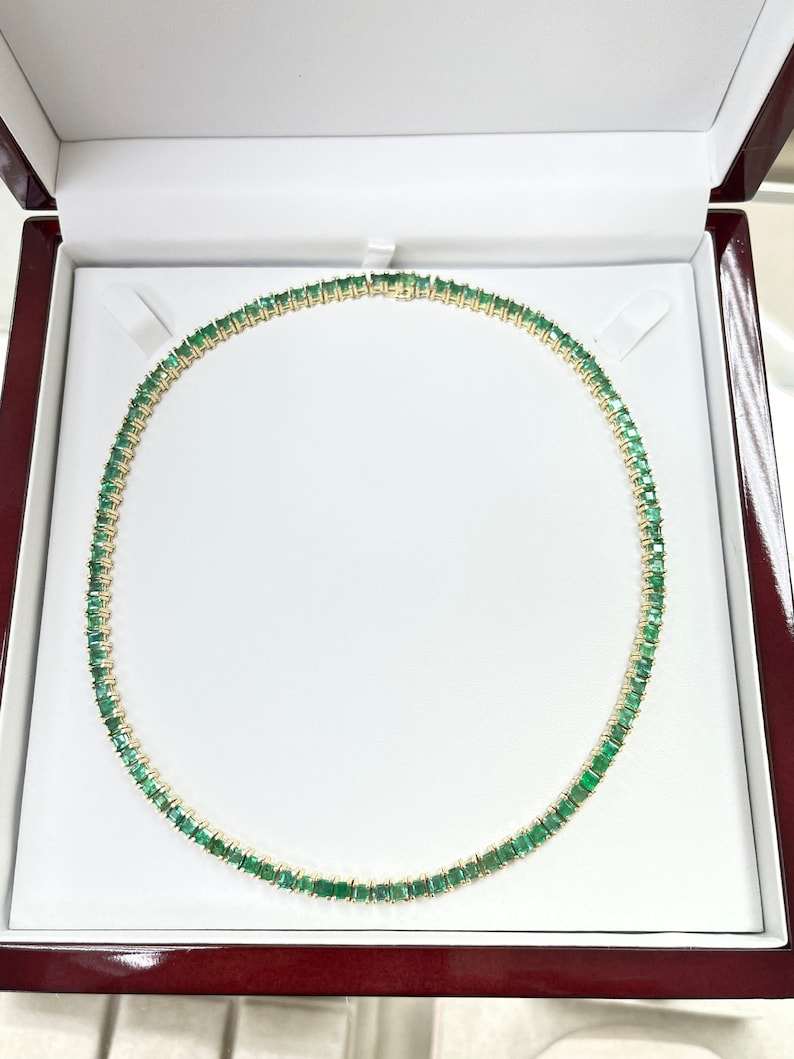 20tcw 14K princess cut emerald tennis prong necklace in yellow gold displayed in open jewelry box