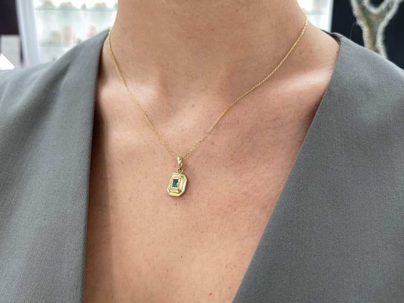 14K gold emerald cut pendant necklace featuring a lush green natural Colombian emerald, bezel set in a unisex design.