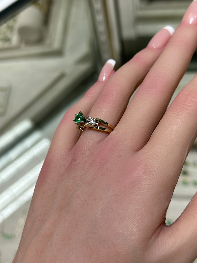 14K gold engagement ring with a 1.25tcw round Colombian emerald center stone and diamond baguette accents in a 6-prong setting.