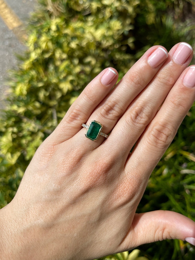 Green emerald cut engagement ring with diamond accents in 14K gold, featuring a 3.59-carat Colombian emerald.