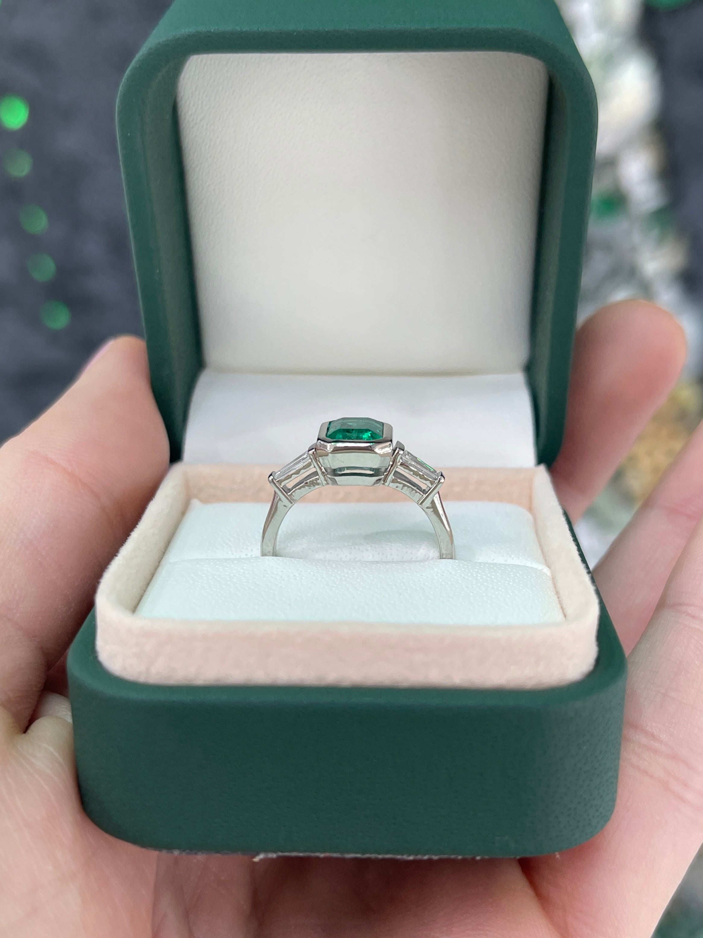 14K gold three-stone engagement ring featuring a 2.03tcw vivid emerald-cut emerald and lab diamond baguette accents.