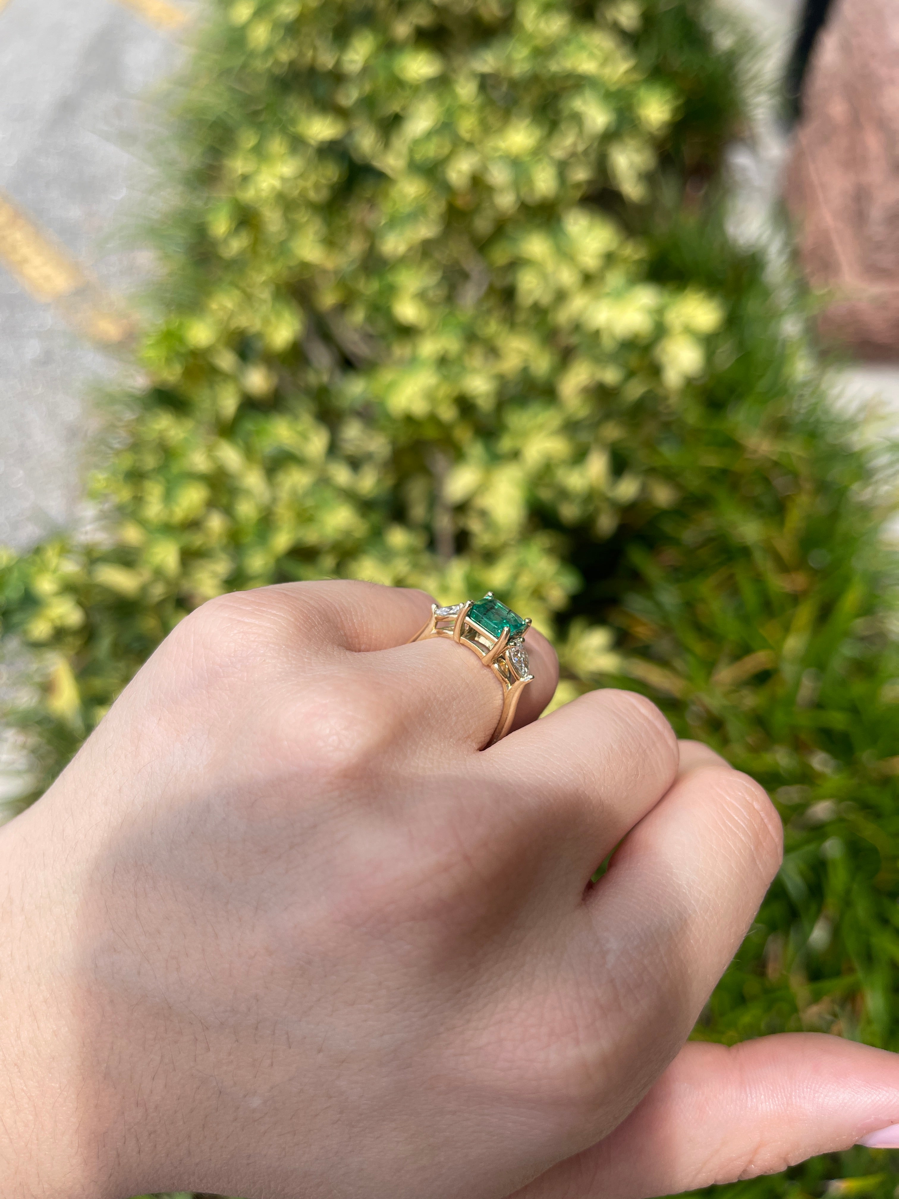 14K gold three-stone engagement ring with natural freckled emerald and lab-created pear-shaped diamonds, featuring an Asscher cut center.