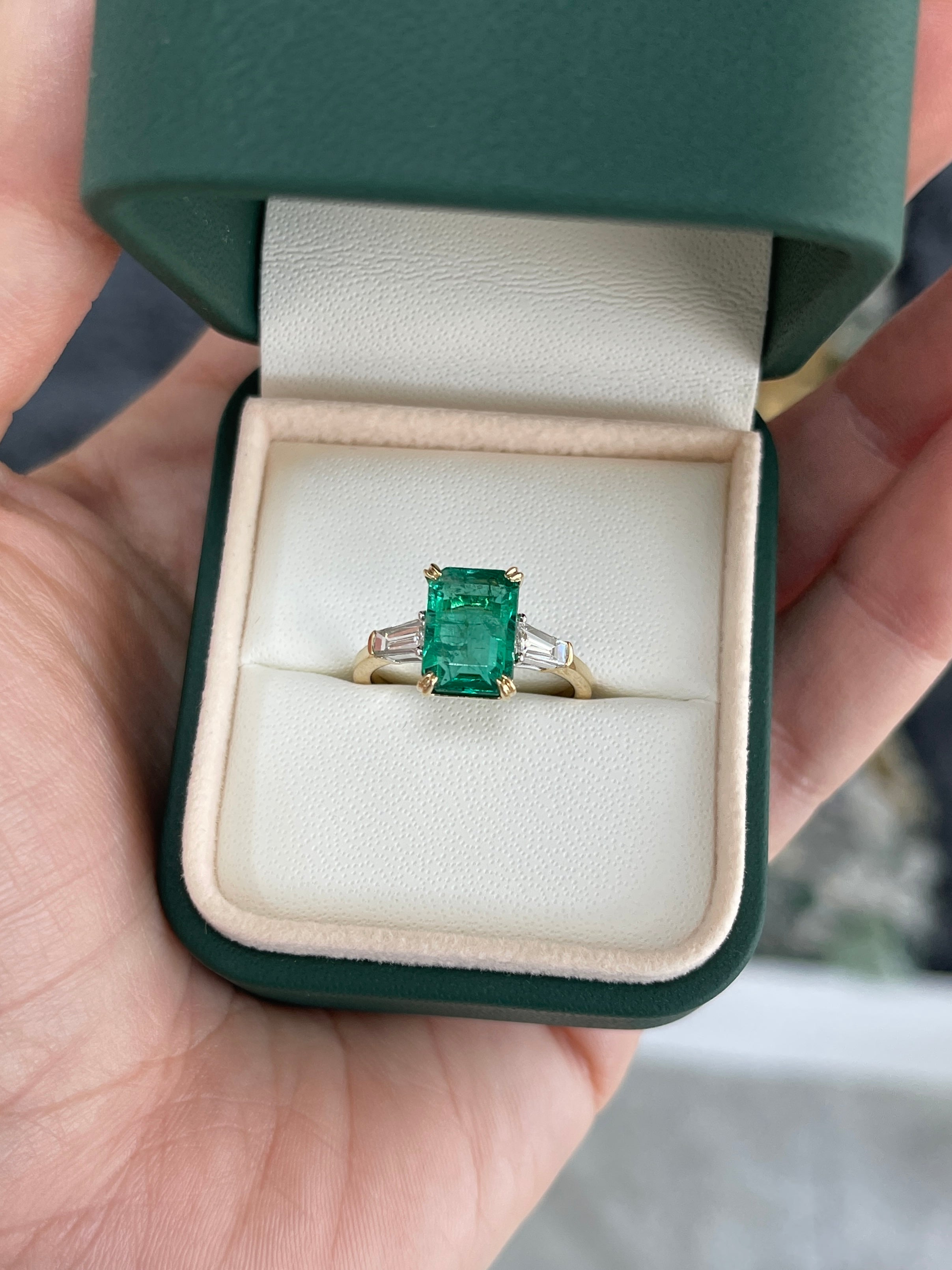14K two-tone emerald cut emerald and baguette diamond three-stone engagement ring by JR Colombian Emeralds, showcasing sparkling gemstones.