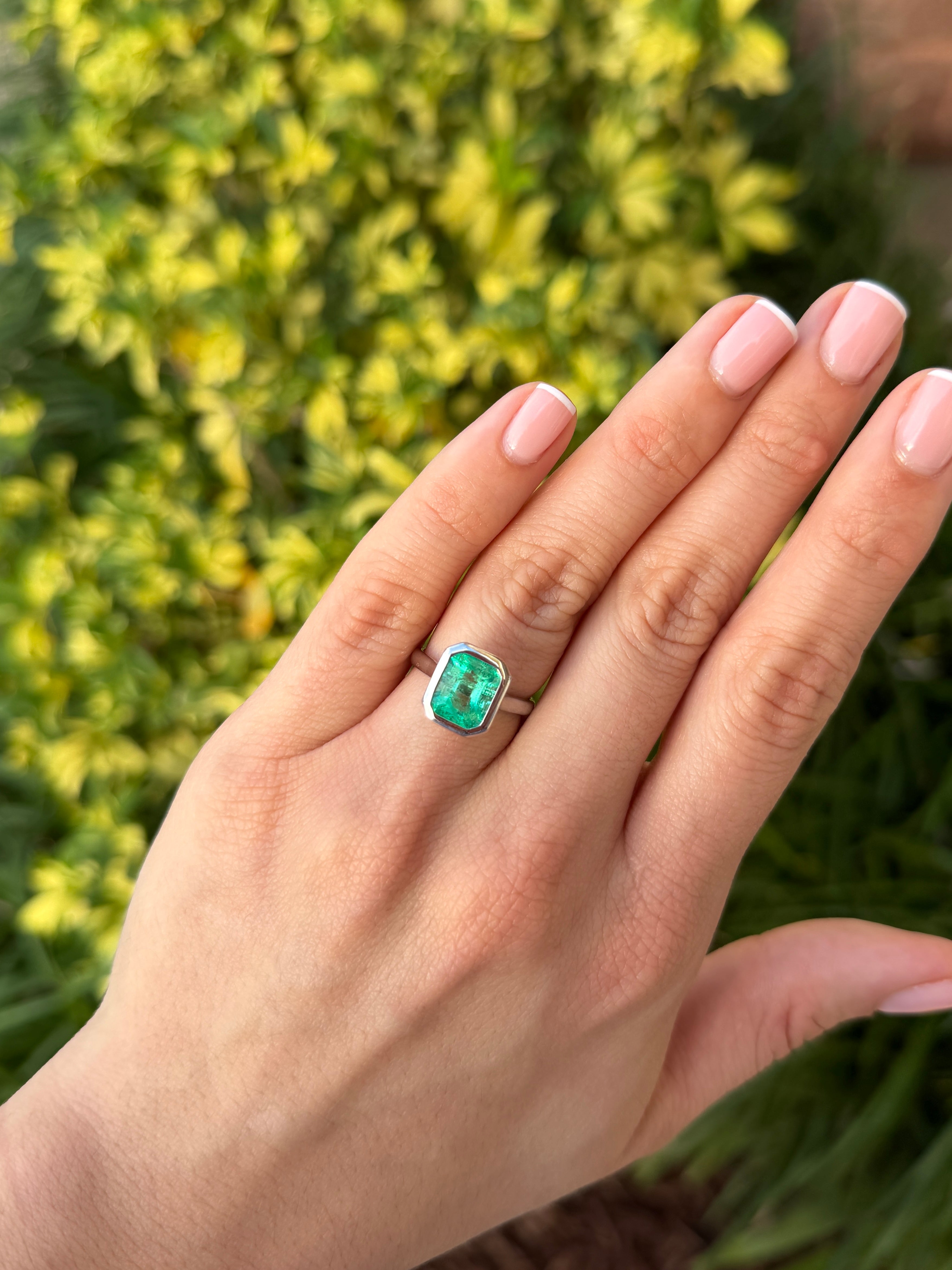 18K white gold ring featuring a 3.46ct bezel-set Colombian emerald solitaire with vibrant green color and intricate detailing.