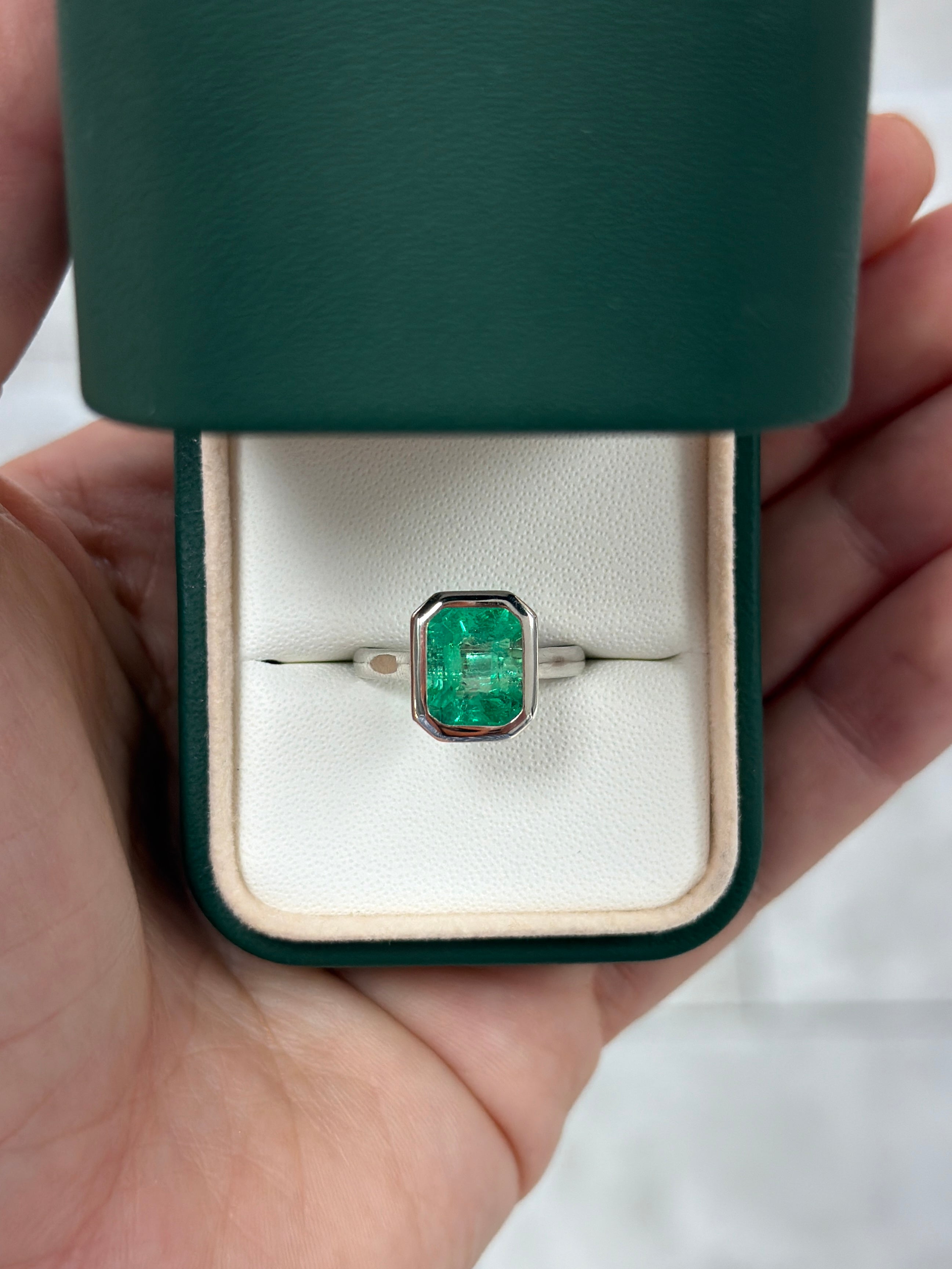 18K white gold ring featuring a 3.46ct bezel-set Colombian emerald solitaire with vibrant green color and intricate detailing.